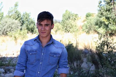 Portrait of young man standing against trees