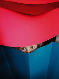Close-up portrait of girl hiding behind paper curtain