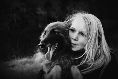 Close-up of young woman embracing dog on field