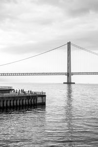 Bridge over river against cloudy sky