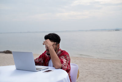 Man using laptop at beach