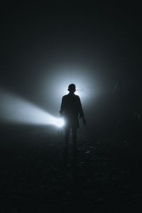 Man with illuminated light standing against sky at night