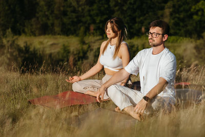 Caucasian woman and man dressed alike , young adult couple meditating outdoors