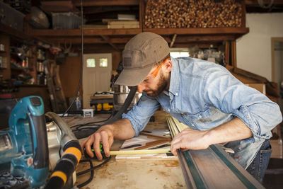 Serious craftsperson measuring wooden art at workshop