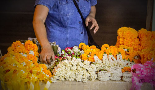 Midsection of woman with floral garland at table