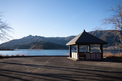 Gazebo by lake against clear blue sky