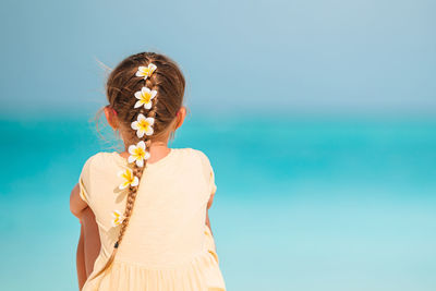 Rear view of girl sitting against sea