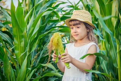 Side view of young woman standing amidst plants