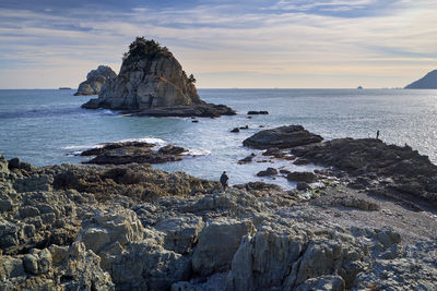 Rock formation at beach against sky during sunset