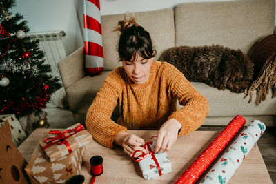 Woman sitting by christmas tree at home