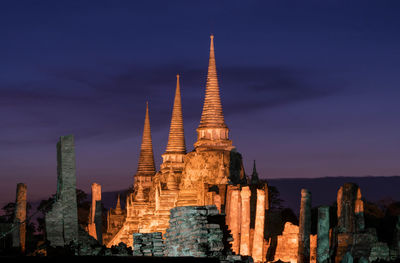 Illuminated stupas against sky at night