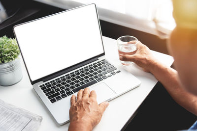 Midsection of man using laptop on table