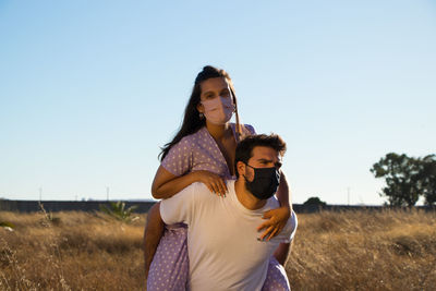 Couple standing on field against clear sky