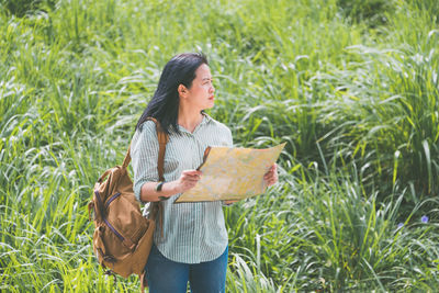 Woman holding map on grassy field