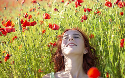 Portrait of young woman with flowers growing on field