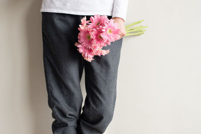 Low section of person standing on pink flower over white background