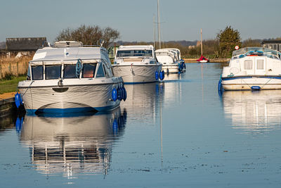 Sailboats moored in lake against sky