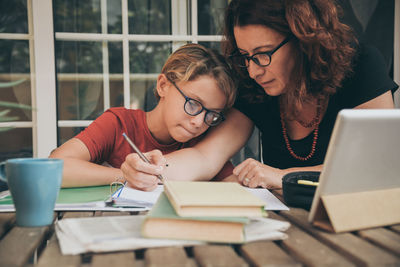 Mother teaching son while sitting by table at home