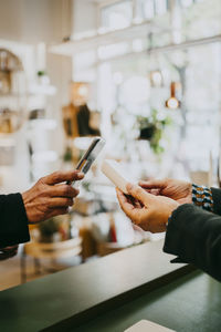 Female owner giving credit card reader to customer while doing online payment in store