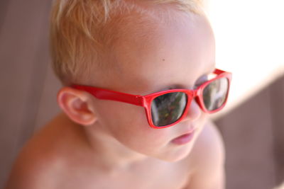 Close-up of shirtless boy wearing sunglass at home