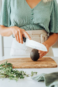 Close up of female hands cutting avocado for healthy breakfast