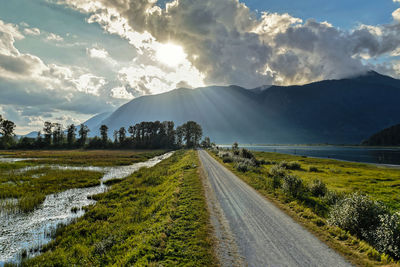 Road leading towards mountains against sky