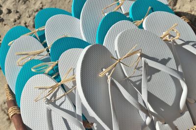 Basket full of pairs of flip flop sandals in white as well as turquoise blue at the beach