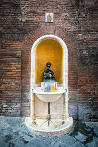 Statue of buddha against brick wall