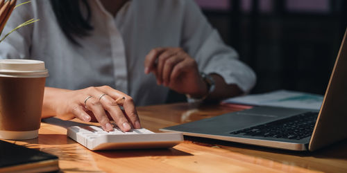 Midsection of woman using laptop on table