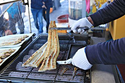 Midsection of person preparing food on barbecue grill