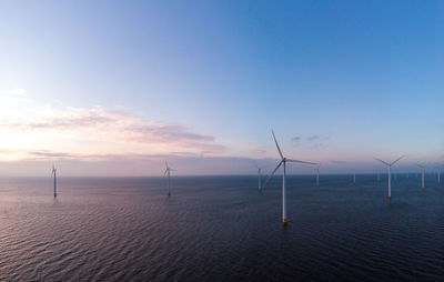Wind turbines in sea against sky during sunset, windmill turbines in the netherlands 