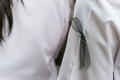 Close-up of safety pin and ribbon on student white uniform