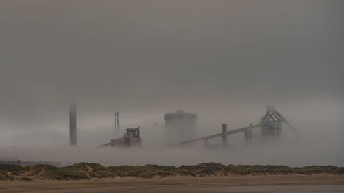 Factory on landscape against sky