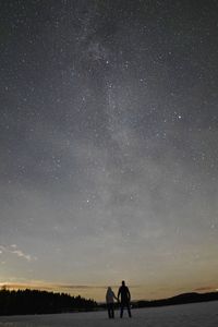 Rear view of silhouette man standing against star field at night