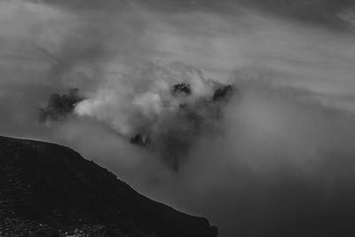Dramatic black and white effect of dolomite peaks half hidden by clouds and fog,