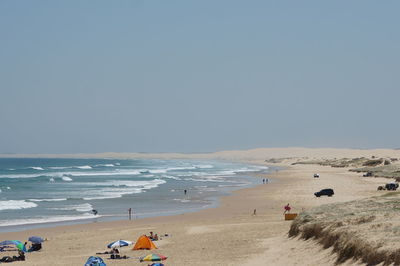 People on beach against clear sky