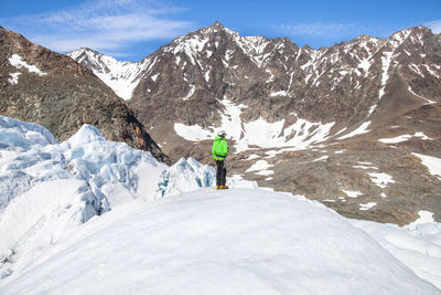 Person standing on snow covered landscape against mountain range