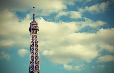Low angle view of communications tower against cloudy sky