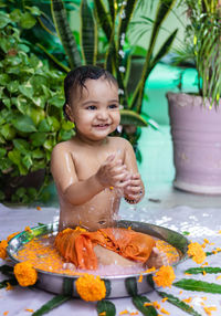 Cute toddler baby boy bathing in decorated bathtub at outdoor from unique perspective