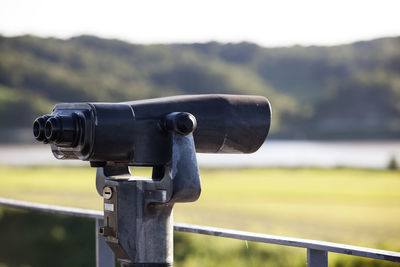 Close-up of coin-operated binocular against river