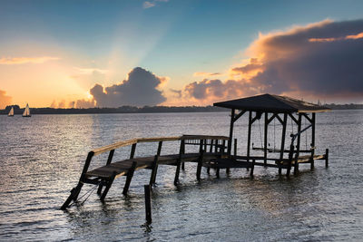 Pier over sea against sky during sunset