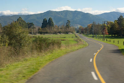 Road leading towards mountains against sky