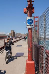 Rear view of man riding bicycle on road