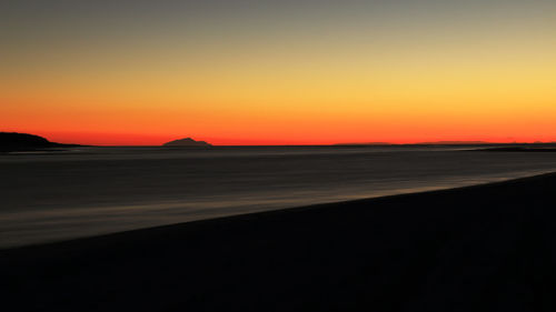 Scenic view of silhouette beach against romantic sky at sunset