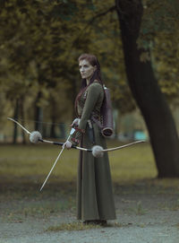 Archer holding bow and arrow while standing outdoors