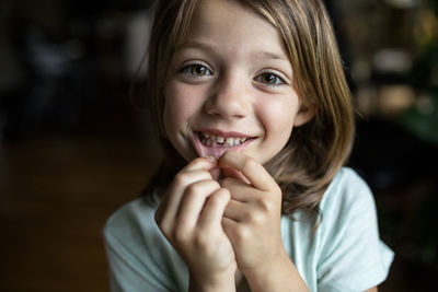 Portrait of happy girl showing tooth gap at home