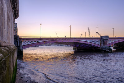 Bridge over river against sky during sunset