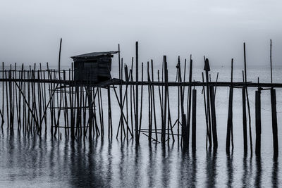 Wooden posts in sea against sky