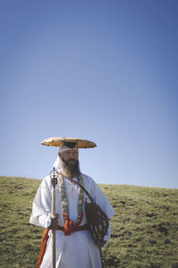 Rear view of man standing on field against clear sky