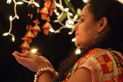 Woman holding illuminated diya at night